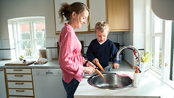 Kvinde og hendes søn skræller gulerødder ved håndvask