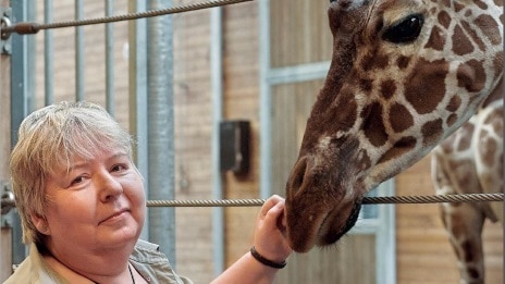 Susanne Bang står ved siden af en girat i Zoologisk Have 